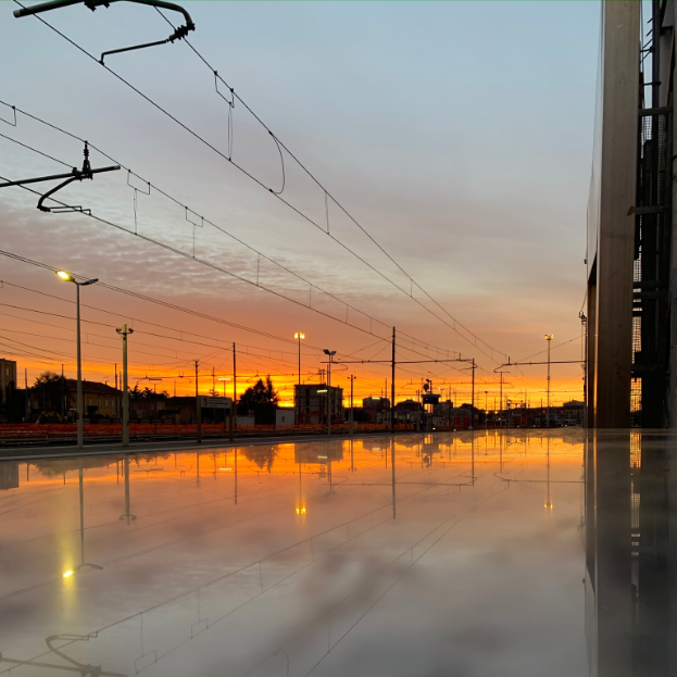 Photo of a reflection on a bench of a sunrise near a train station