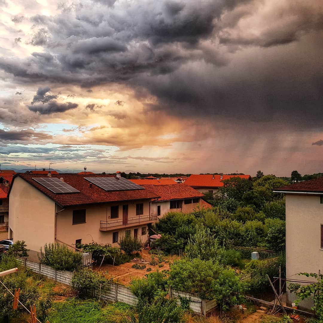 Photo of a small village where the sky is split between sun and a thunderstorm